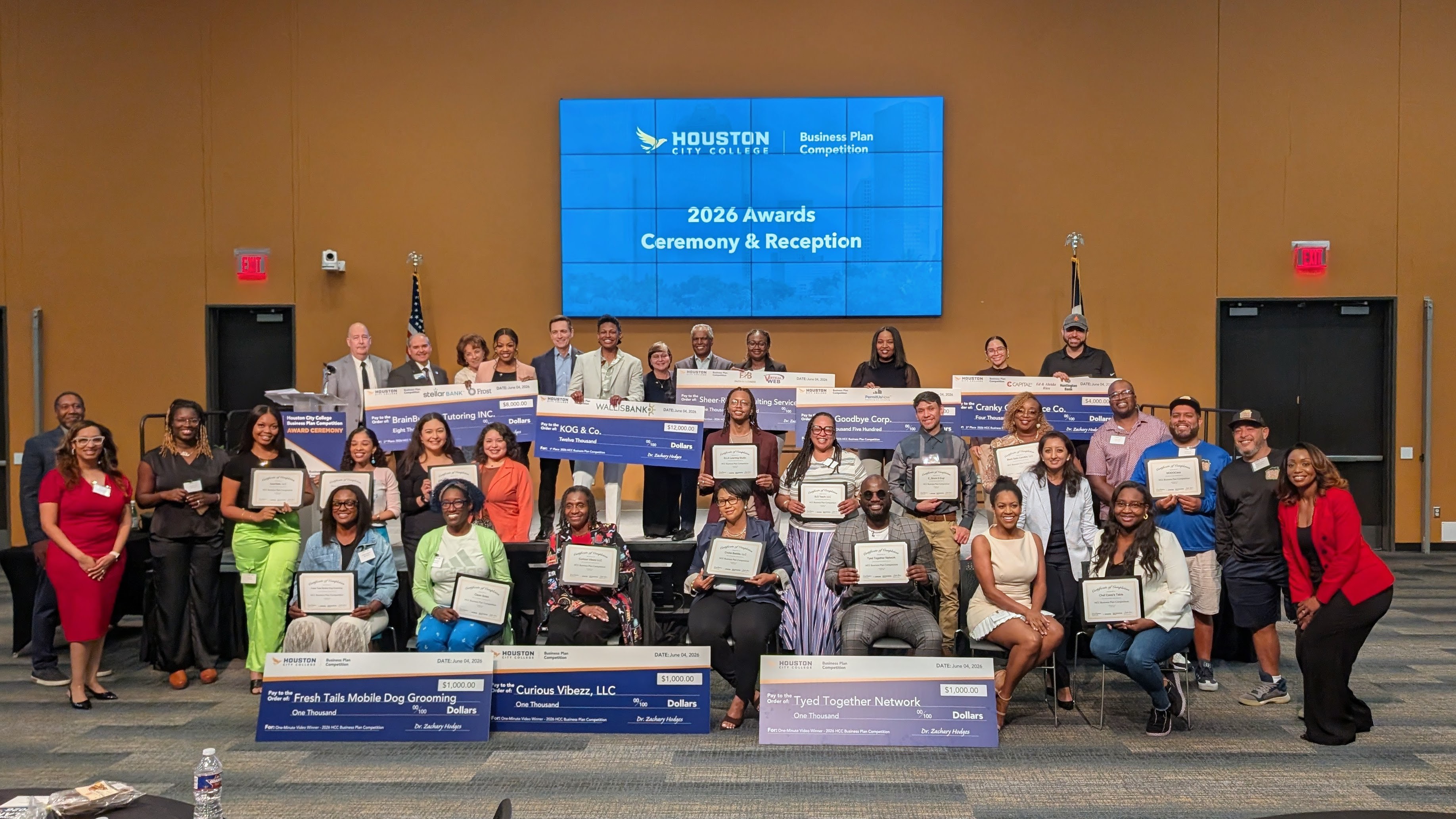 2026 HCC Business Plan Competition Winners, Graduates and Sponsors all in one picture. Winners are posing by holding their cash prize checks and graduates are posing with their certificates.